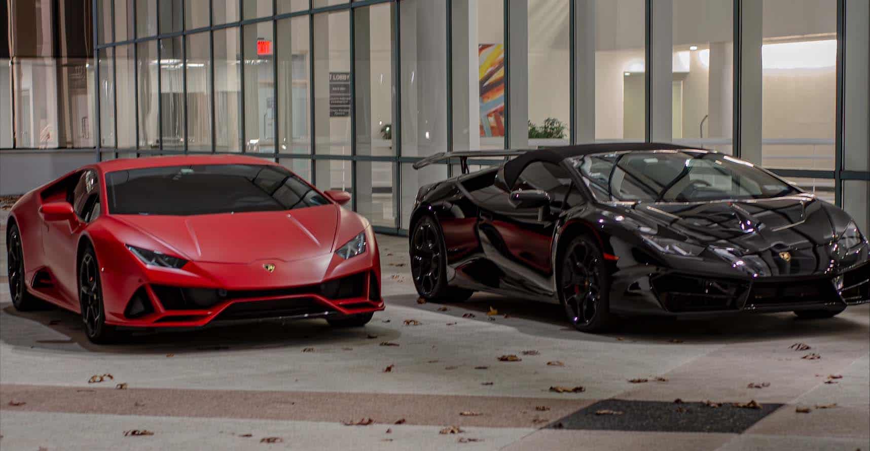 Red and black Lamborghini sports cars parked outside.