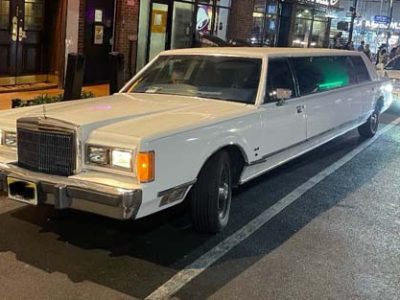 White stretch limousine parked on city street at night