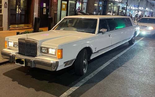White stretch limousine parked on city street at night