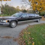 Black stretch limousine parked on suburban street in autumn