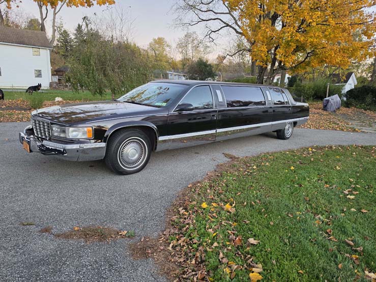 Black stretch limousine parked on suburban street in autumn