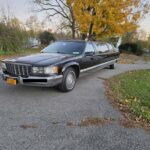 Black stretch limousine parked on a suburban driveway in autumn