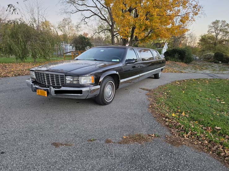 Black stretch limousine parked on a suburban driveway in autumn