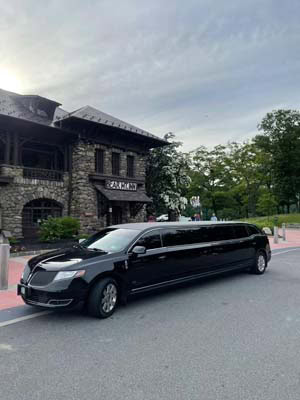 Black stretch limousine parked outside stone building