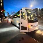 White coach bus parked on city street at night
