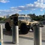 Tan military Humvee parked outside urban building