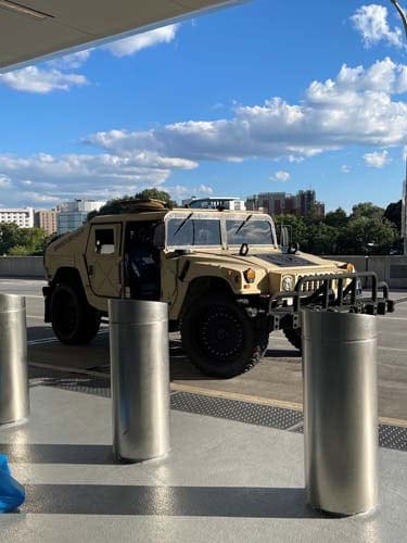 Tan military Humvee parked outside urban building
