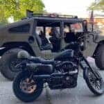Black motorcycle parked before military-style Humvee vehicle