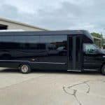 Black shuttle bus parked outside industrial building
