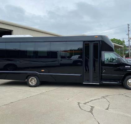 Black shuttle bus parked outside industrial building