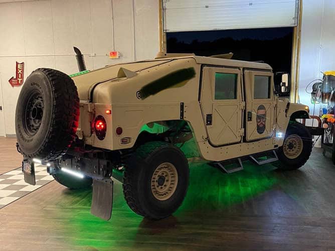 Tan Humvee with green underglow inside garage