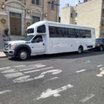 White shuttle bus parked on a street near a church