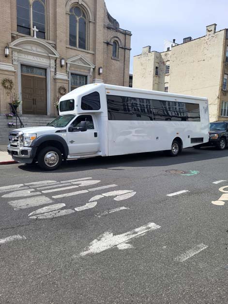 White shuttle bus parked on a street near a church