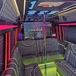 Neon-lit party bus interior with seating and pole