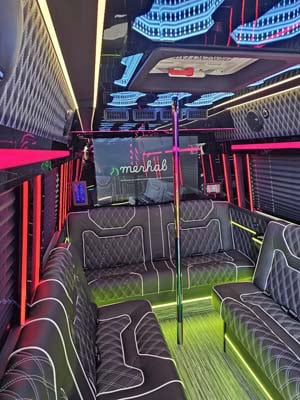 Neon-lit party bus interior with seating and pole