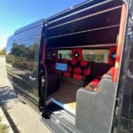 Luxurious black shuttle van interior with custom red leather seats.