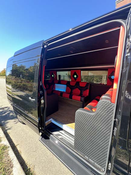 Luxurious black shuttle van interior with custom red leather seats.