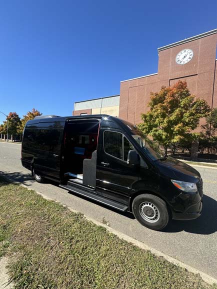 Black Mercedes-Benz Sprinter van parked in front of brick building