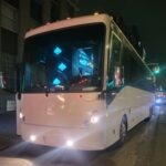 White coach bus driving on city street at night