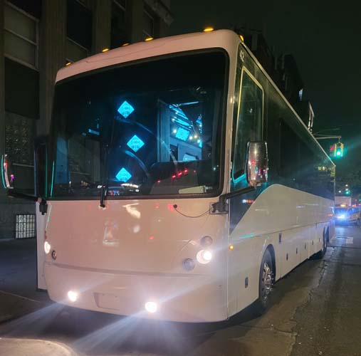 White coach bus driving on city street at night