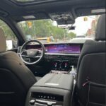 Luxury car interior with wide digital displays and city street.