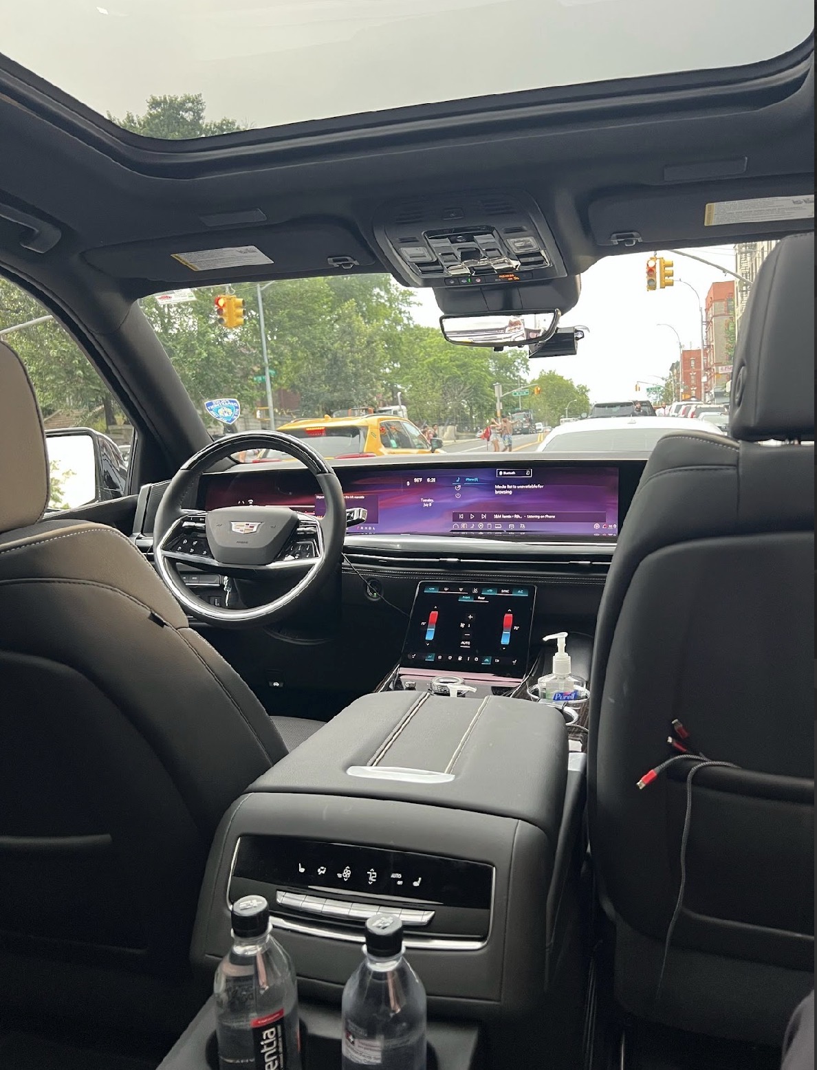 Luxury car interior with wide digital displays and city street.