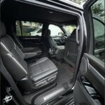 Black luxury SUV interior with open door and captain's chairs.