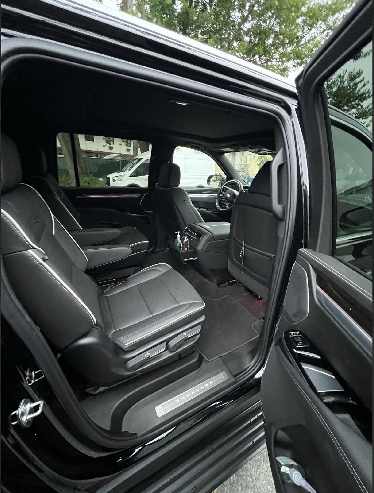 Black luxury SUV interior with open door and captain's chairs.