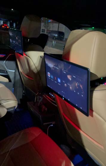 Luxury car rear seats with dual entertainment screens at night