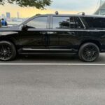 Black luxury SUV parked beside waterfront city skyline
