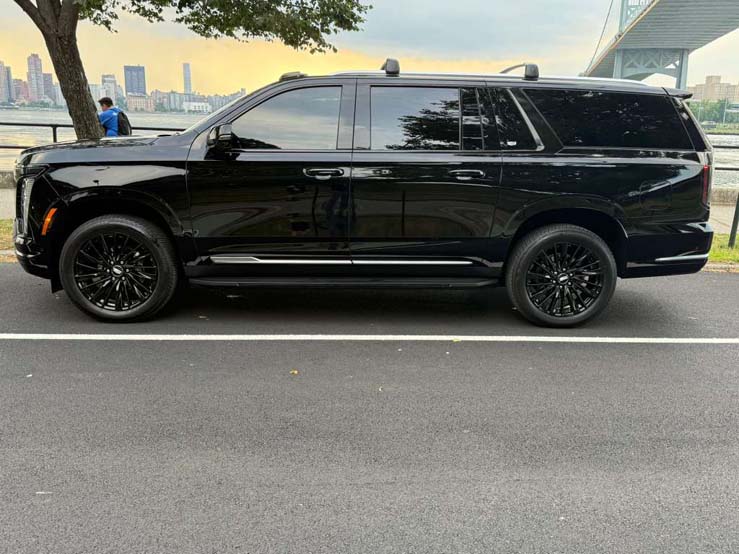 Black luxury SUV parked beside waterfront city skyline