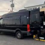 Black accessible van with wheelchair lift deployed outside restaurant