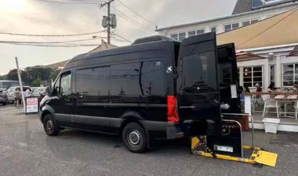 Black accessible van with wheelchair lift deployed outside restaurant