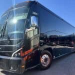 Black luxury motorcoach bus parked outdoors in daylight