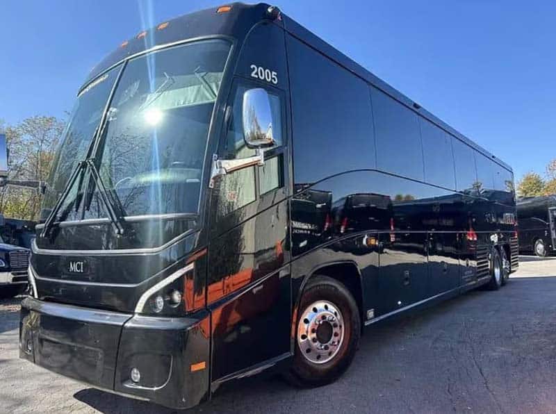 Black luxury motorcoach bus parked outdoors in daylight