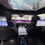 Luxury car interior with rear entertainment screens and panoramic sunroof