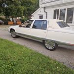 White vintage limousine parked in residential driveway