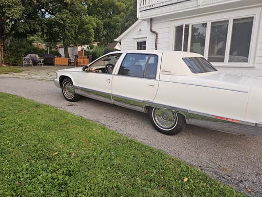 White vintage limousine parked in residential driveway