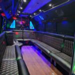 Luxury party bus interior with quilted seating and blue lighting.