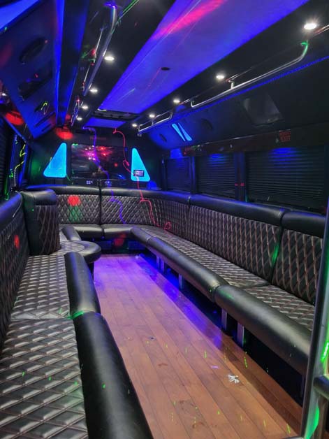 Luxury party bus interior with quilted seating and blue lighting.