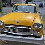 Damaged yellow vintage car with detached front bumper