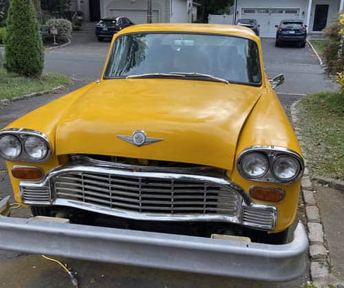 Damaged yellow vintage car with detached front bumper