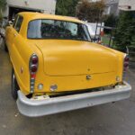 Rear view of bright yellow vintage car with stacked taillights.