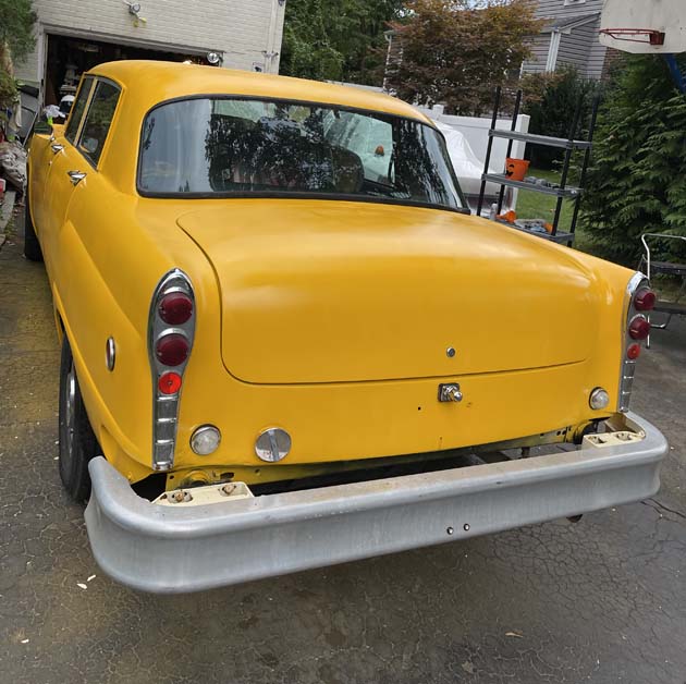 Rear view of bright yellow vintage car with stacked taillights.