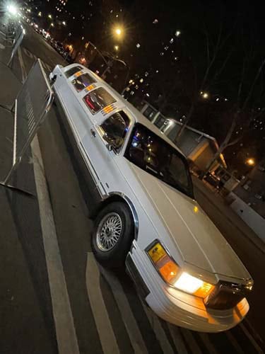 White stretch limousine parked on city street at night