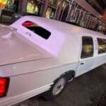 White stretch limousine parked on city street at night