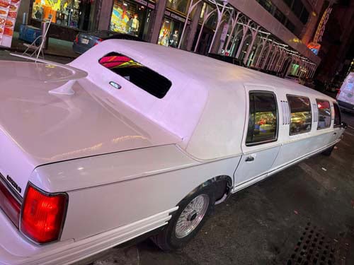 White stretch limousine parked on city street at night