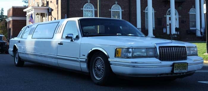 White stretch limousine parked outside brick building