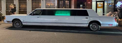 White stretch limousine parked on city street at night