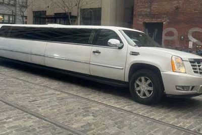 White stretch SUV limousine on cobblestone street